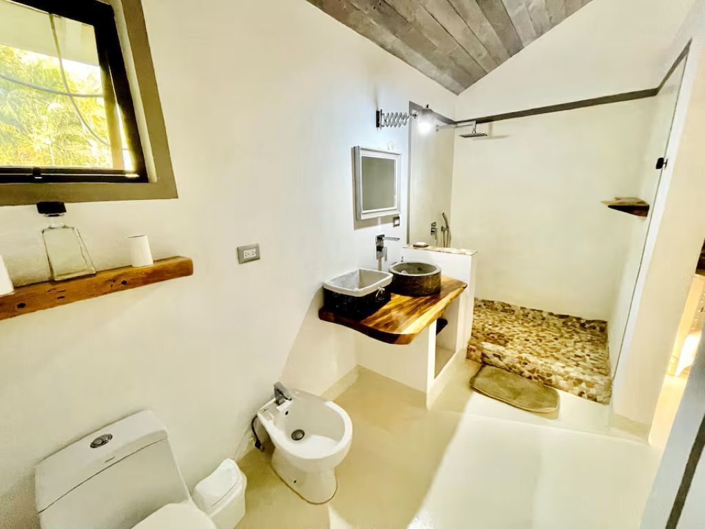 Uma casa de banho moderna com sanita, bidé, toucador com espelho e zona de duche.