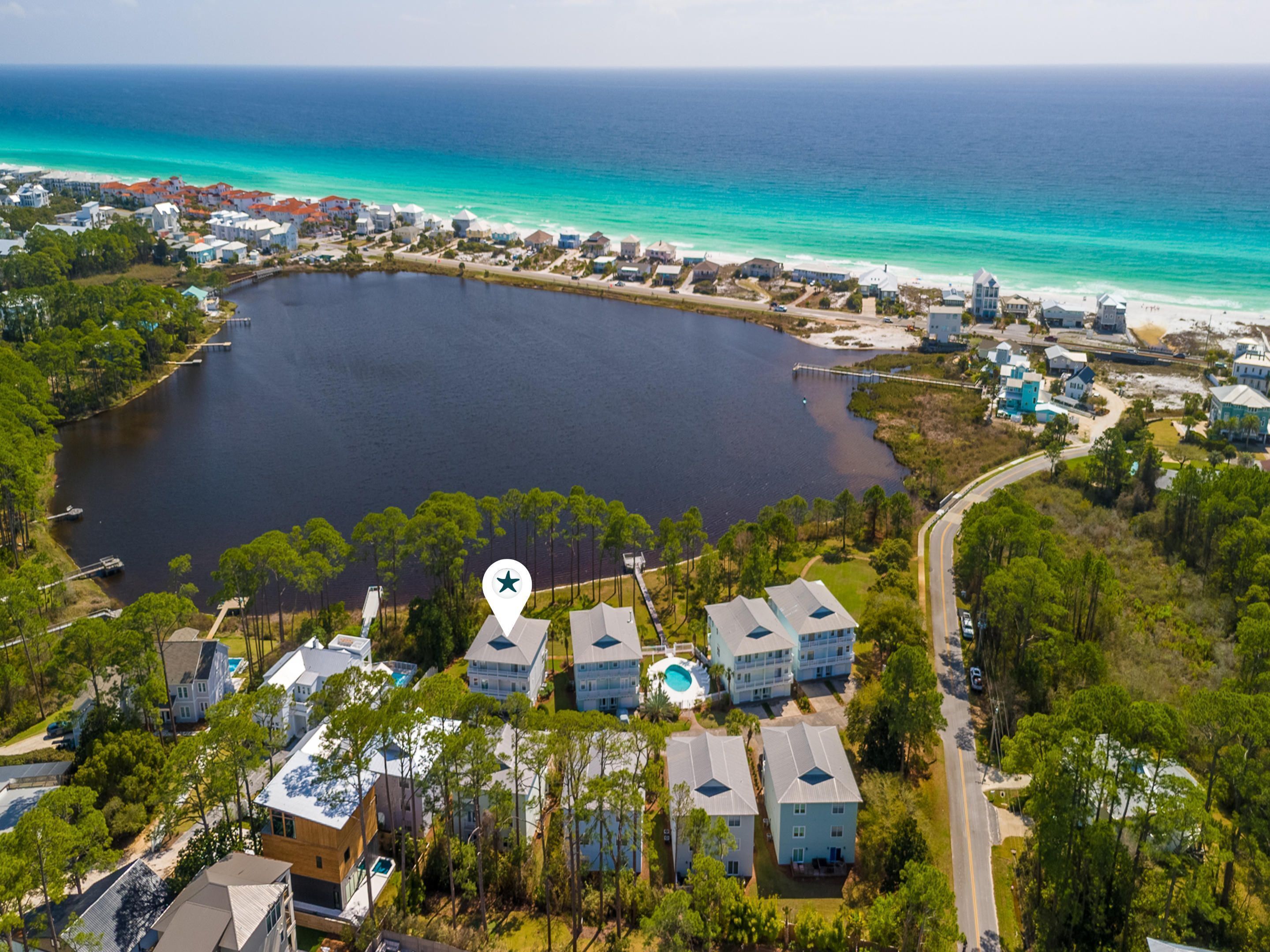 An aerial view of a coastal area with a large body of water, a marina, and residential buildings.