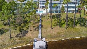 Un hotel sulla costa con un lungo molo che si protende nell'acqua, circondato da rigogliosa vegetazione e diversi edifici con balconi.
