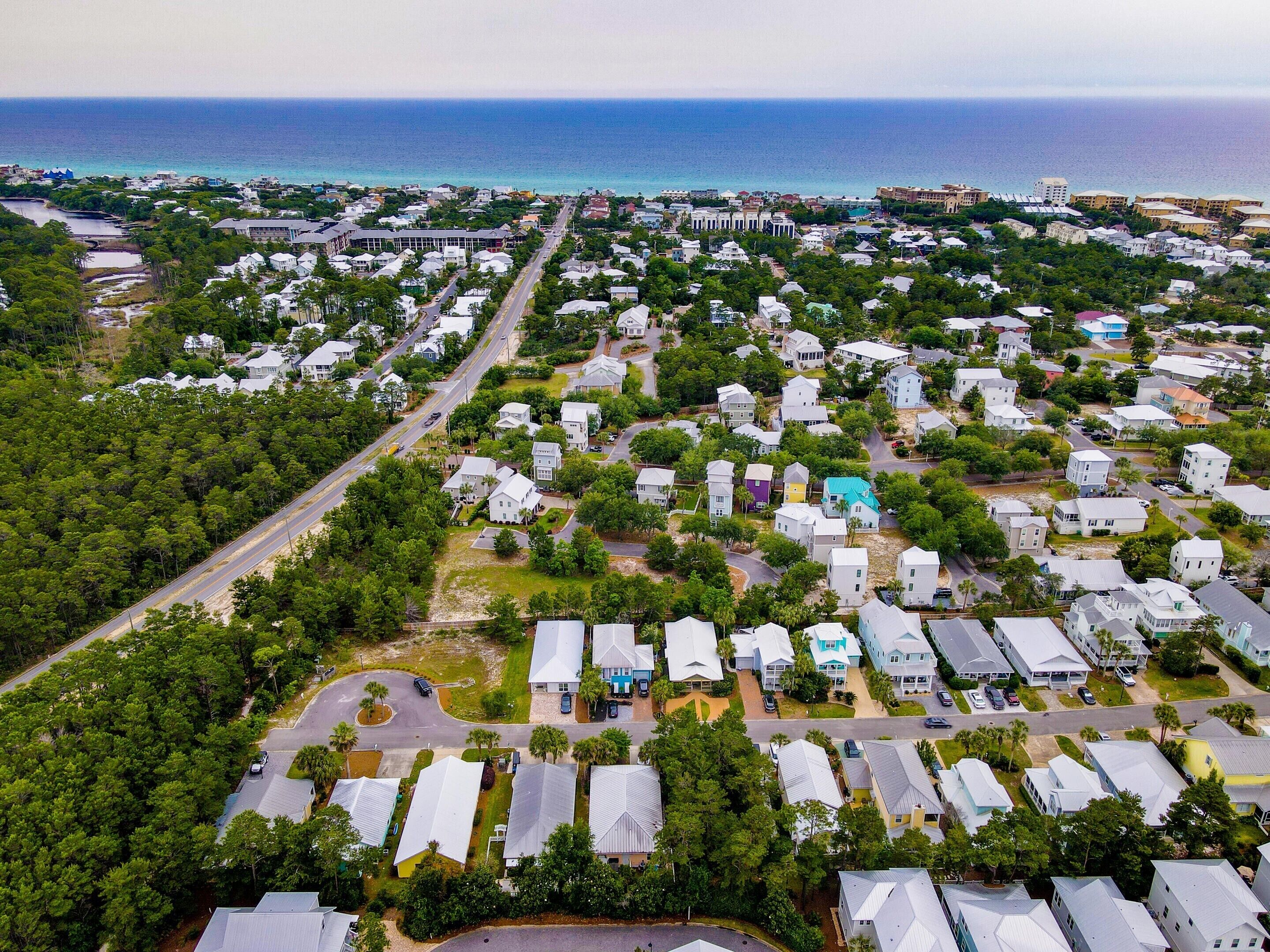 An aerial view of a residential area with houses, roads, and a coastline.