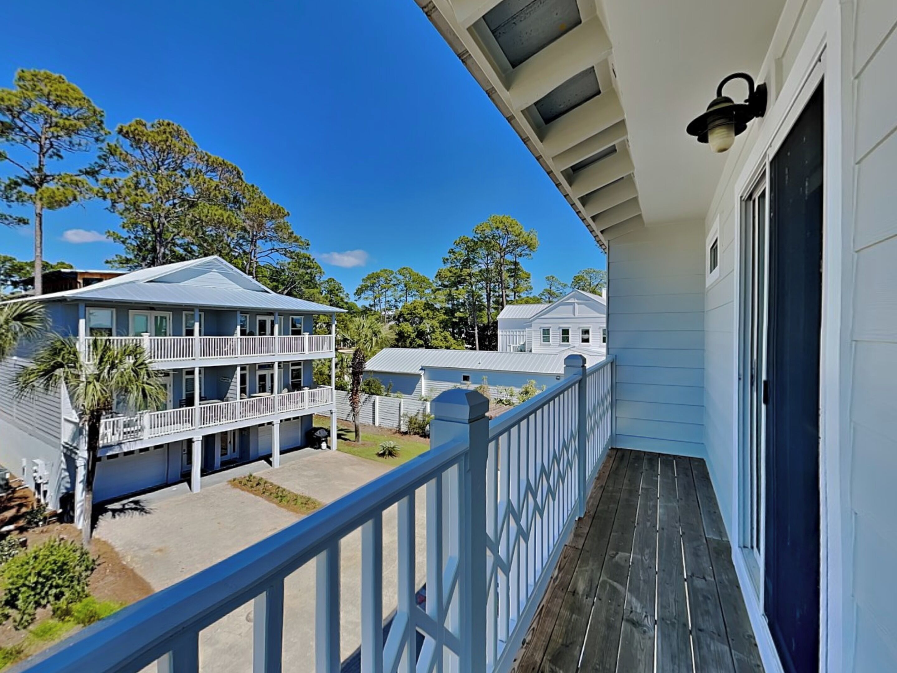 A two-story building with a balcony, a wooden deck, and a clear view of surrounding houses and trees.