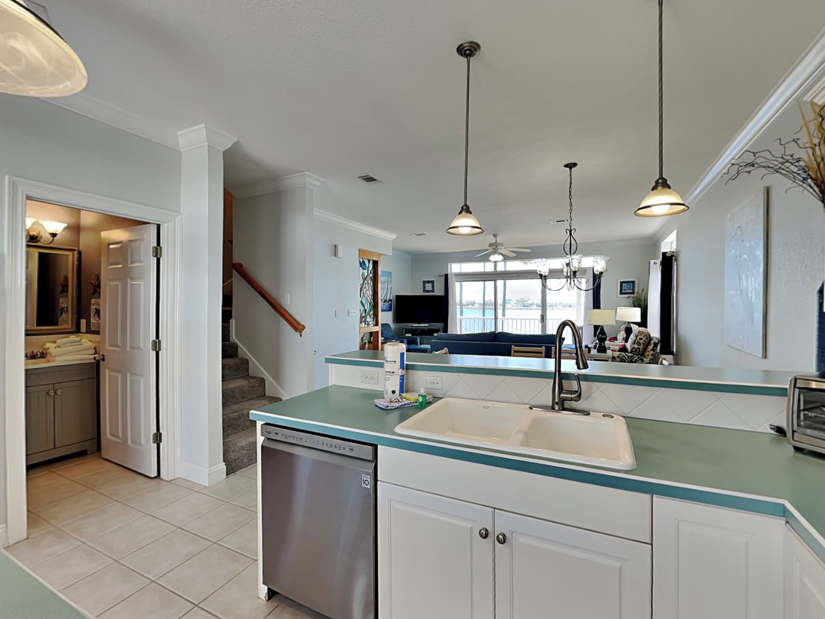 A modern kitchen with a dishwasher, a sink, and a dining area with a TV.