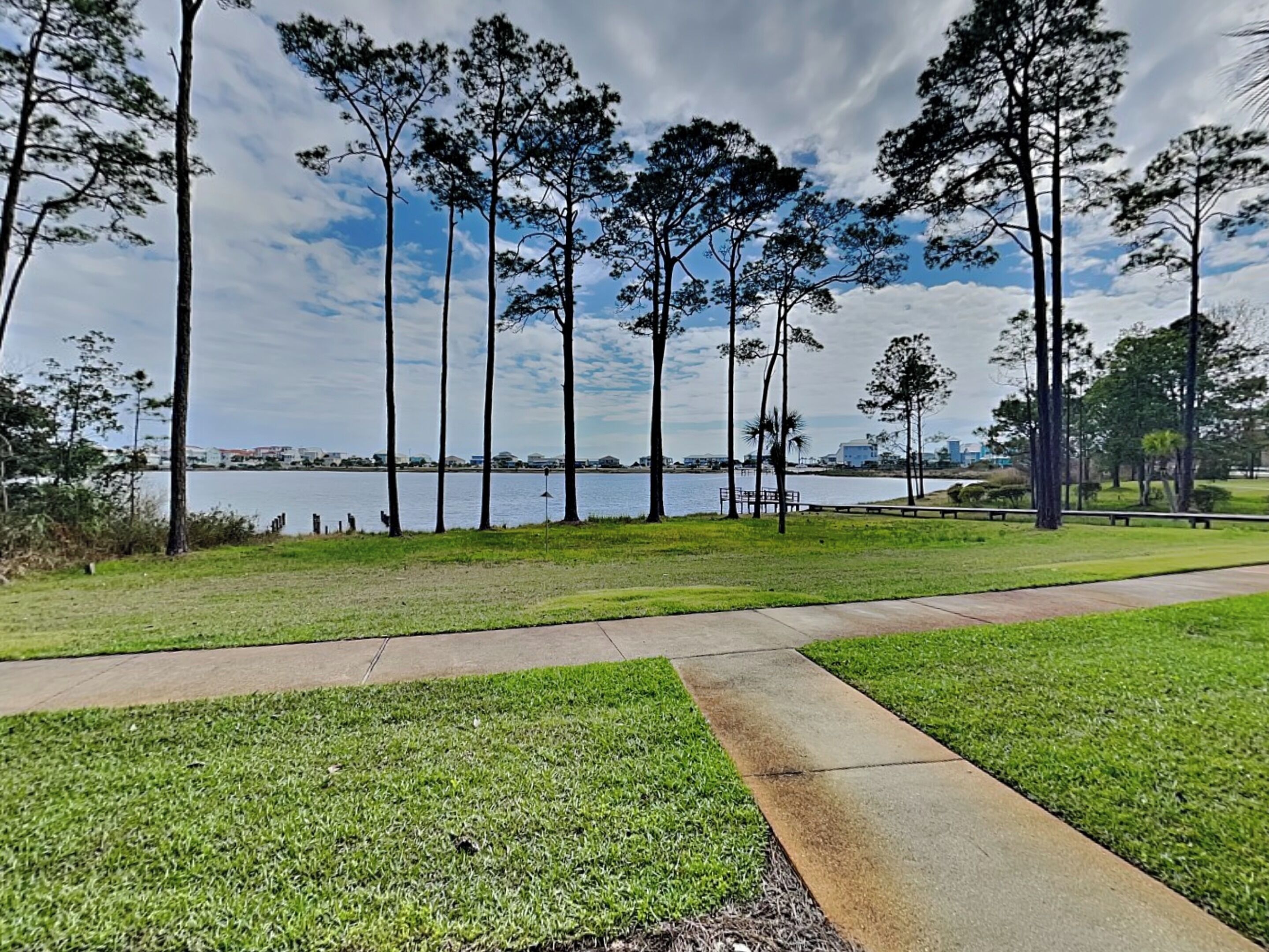A park with a walking path, grassy areas, and tall trees.