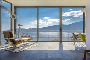 Ein großzügiger Balkon mit Blick auf das Meer und die Berge, moderne Möbel und ein Teleskop.
