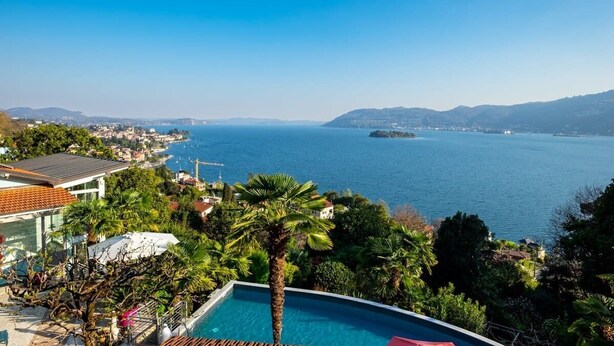 A poolside view overlooking a coastal town with a clear view of the sea and distant hills. - Luxury Lake Maggiore villa (Pallanza)