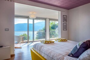 Une chambre avec un grand lit, une vue sur la mer et un balcon équipé d’une chaise.