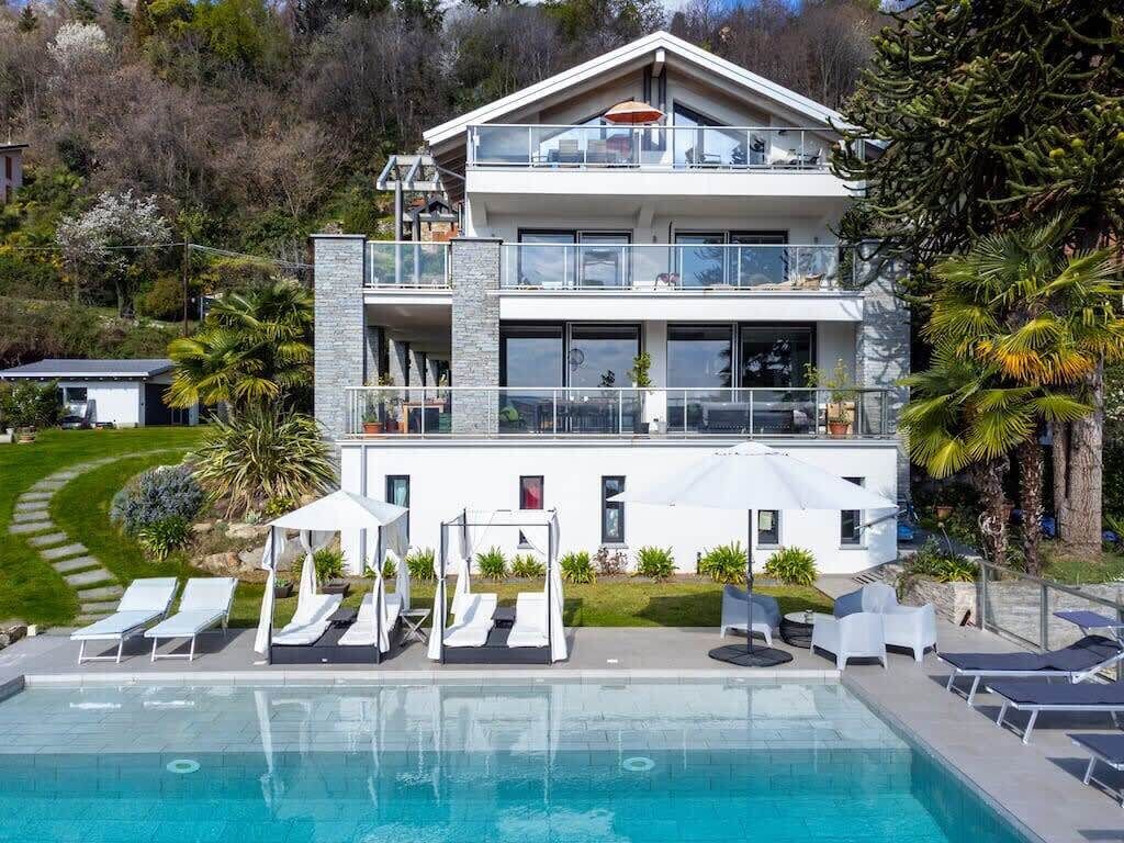 A modern two-story house with a swimming pool, outdoor seating, and a well-maintained garden.