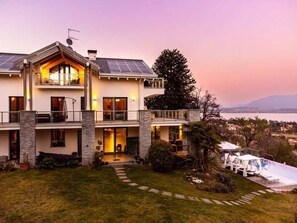 A two-story house with a balcony, solar panels, and a view of a body of water. - Maggiore Lake apartment (Lesa)