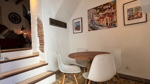 Ein Essbereich mit Holztisch und weißen Stühlen, eine Treppe mit Holzstufen und fliesenbelagtem Boden.