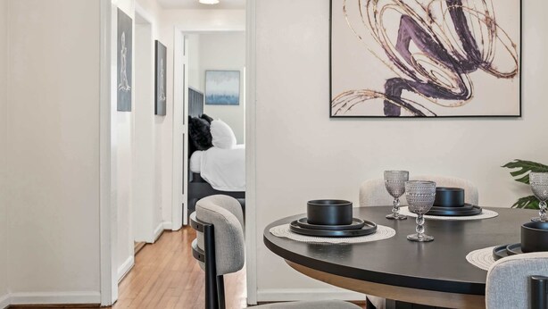 Un comedor con una mesa redonda, sillas y un cuadro abstracto moderno en la pared.