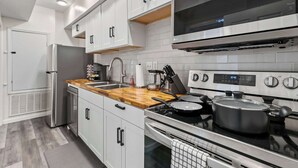 Una cocina moderna con armarios blancos, un refrigerador de acero inoxidable, un horno empotrado y un microondas sobre la estufa.