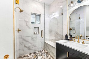 Ein Badezimmer mit Dusche, Waschtisch und einem großen Spiegel.