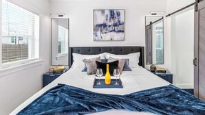 Una camera d'albergo con un letto, un comodino, una finestra e una porta.