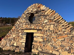 Una construcció de pedra amb una obertura central, envoltada d'un conjunt circular de pedres.
