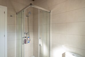 A glass-enclosed shower with a handheld showerhead, a glass door, and a tiled wall. - Villa La Finca Country House with Mountain Views, Wi-Fi and Air Conditioning (Obejo)