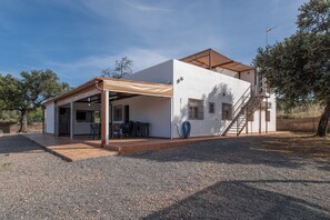 Une maison moderne dotée d’un patio couvert, d’un escalier et d’un tuyau d’arrosage.