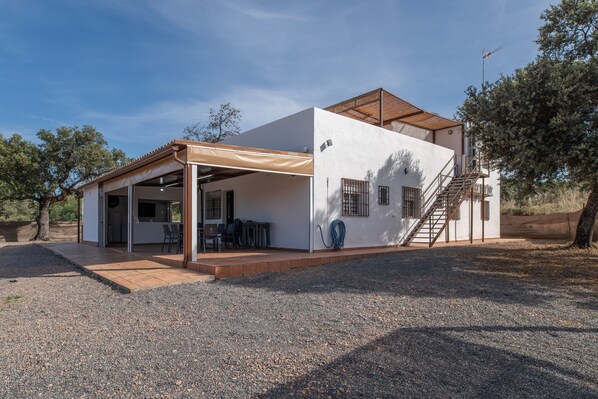 A modern house with a covered patio, a staircase, and a hose.