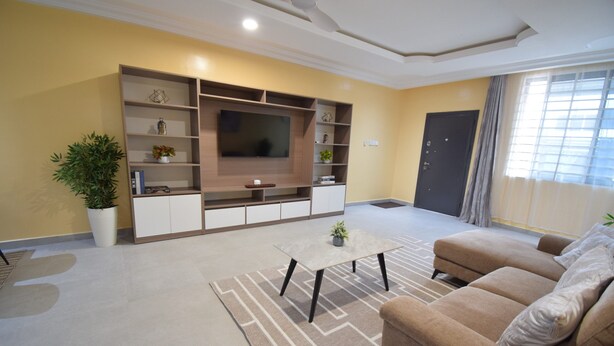 A living room with a sofa, a coffee table, a TV, and a bookshelf. - A cosy and well presented 2 bedroom apartment (JXR2+94H, Sakumono)