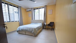 A bedroom with a bed, a chair, and a window with curtains. - A cosy and well presented 2 bedroom apartment (JXR2+94H, Sakumono)