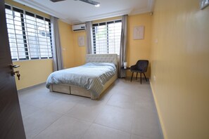 Ein Schlafzimmer mit einem Bett, einem Sessel und einem Fenster mit Vorhängen.