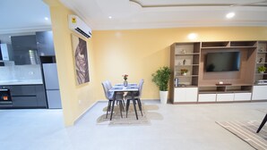 A modern living room with a dining area, a flat-screen TV, and a kitchen in the background. - A cosy and well presented 2 bedroom apartment (JXR2+94H, Sakumono)