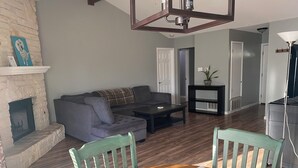 A living room with a fireplace, a sectional sofa, a coffee table, and a dining table with chairs. - Casa Azul - Home w/fenced yard (Buda)