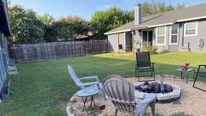A backyard with a fire pit, two chairs, and a table. - Casa Azul - Home w/fenced yard (Buda)