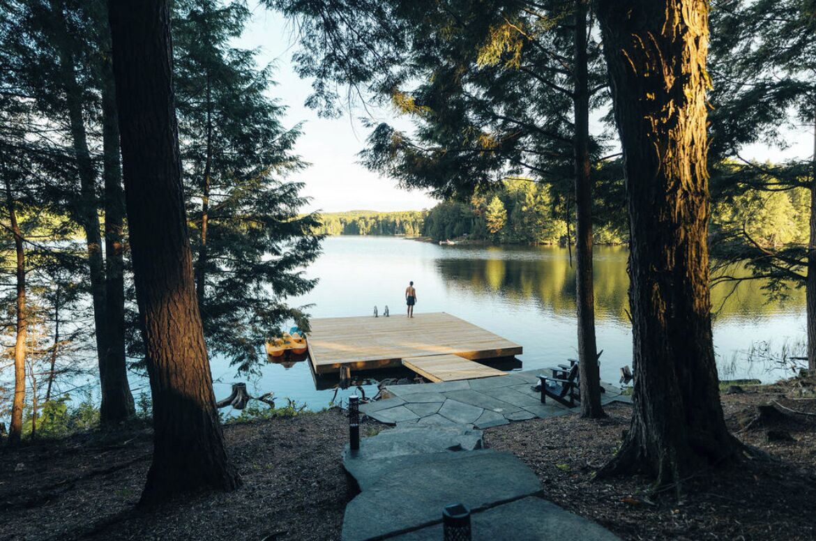 A wooden dock extending into a calm lake surrounded by tall trees.