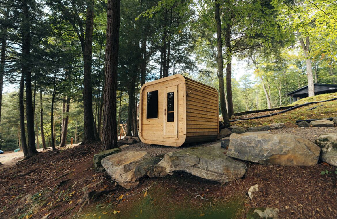 A wooden cabin in a forest, surrounded by large rocks and trees.