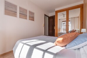 A bedroom with a bed, a wardrobe, and a door leading to another room. - 'Casita Blanca Seafront Apartment' with Sea Views, Pool, and Wi-Fi (Miami Platja)