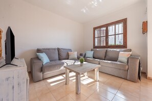 A living room with a sofa set, a coffee table, and a TV. - 'Casita Blanca Seafront Apartment' with Sea Views, Pool, and Wi-Fi (Miami Platja)