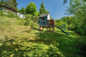 Un parque infantil con columpios, un tobogán y una pequeña estructura de madera.