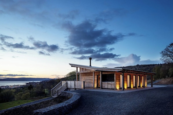 A modern building with a sloped roof, a chimney, and a staircase leading to a covered area.