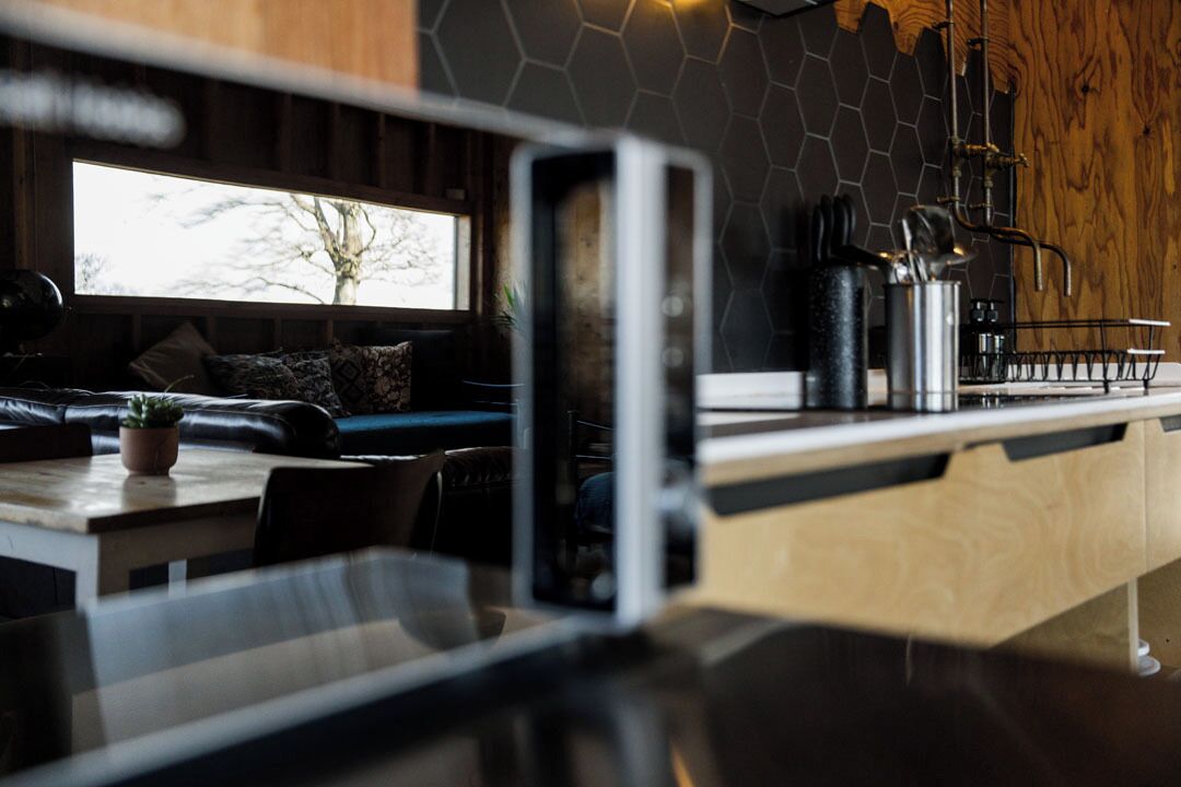 A modern kitchen with a wooden countertop, a built-in stove, and a window with a view of trees.