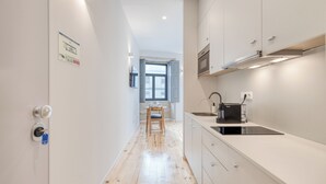 A narrow kitchen with a window, a dining table, and a built-in stove. - FindMe inPorto Bonfim 1F (Porto)