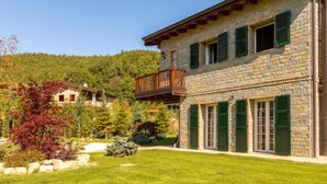 A stone building with a balcony, green shutters, and a well-maintained lawn. - Easylife - Bobbio - Panoramic villa with garden (Bobbio)