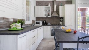 A kitchen with white cabinets, a brick wall, a microwave, and a stove. - Easylife - Bobbio - Panoramic villa with garden (Bobbio)