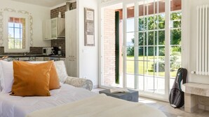 A bedroom with a bed, a bedside table, a window with a view of a garden, and a kitchen area with cabinets and appliances. - Easylife - Bobbio - Panoramic villa with garden (Bobbio)