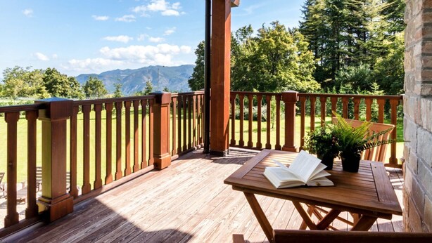 A wooden deck with a table and chairs, a book, and a potted plant. - Easylife - Bobbio - Panoramic villa with garden (Bobbio)