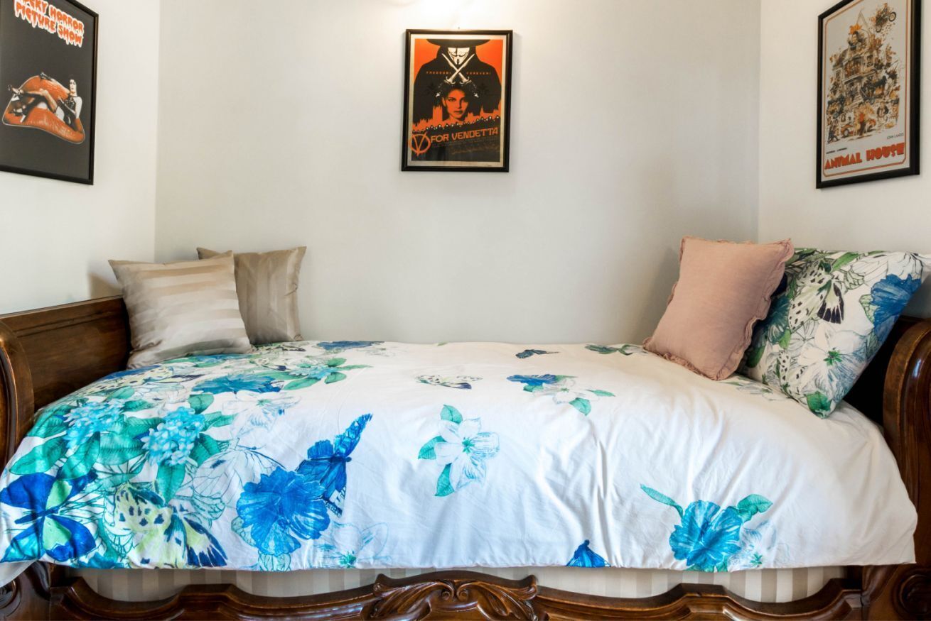 A bedroom with a floral bedspread, a wooden headboard, and two pillows.
