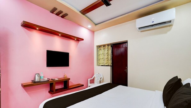 Un dormitorio con cama, televisor montado en la pared, escritorio con silla y aire acondicionado.