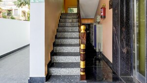 Una escalera con escalones de granito y barandilla de madera, que conduce a un pasillo con un extintor de incendios montado en la pared.