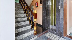 Una escalera con un letrero de salida verde, un extintor y un ascensor.