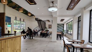 Un interior moderno con un mostrador de recepción de madera, una escalera de caracol y grandes ventanales con vistas al exterior.