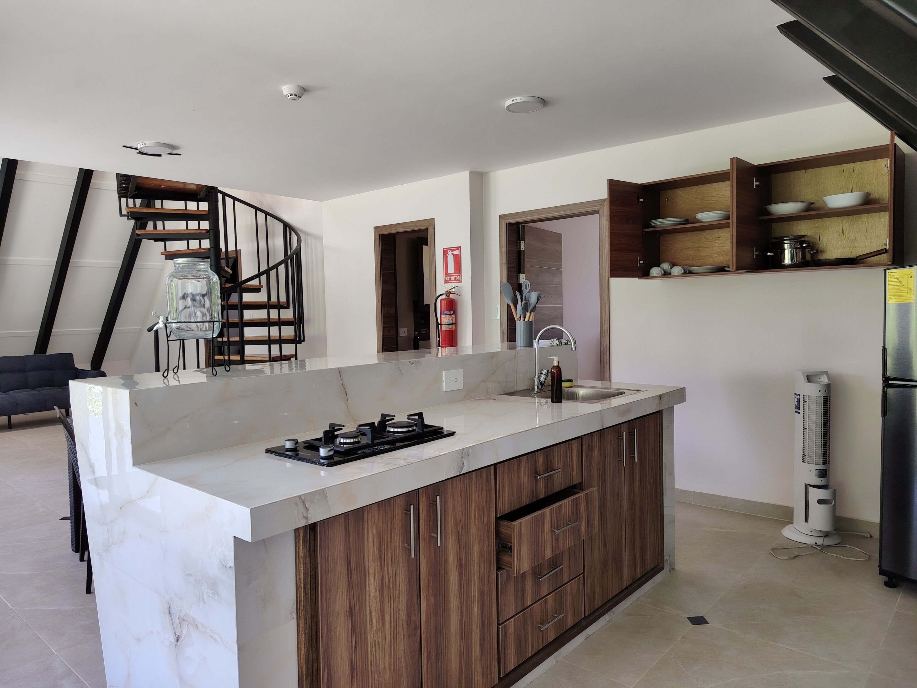 A modern kitchen with a marble countertop, wooden cabinets, a built-in stove, and a small island.