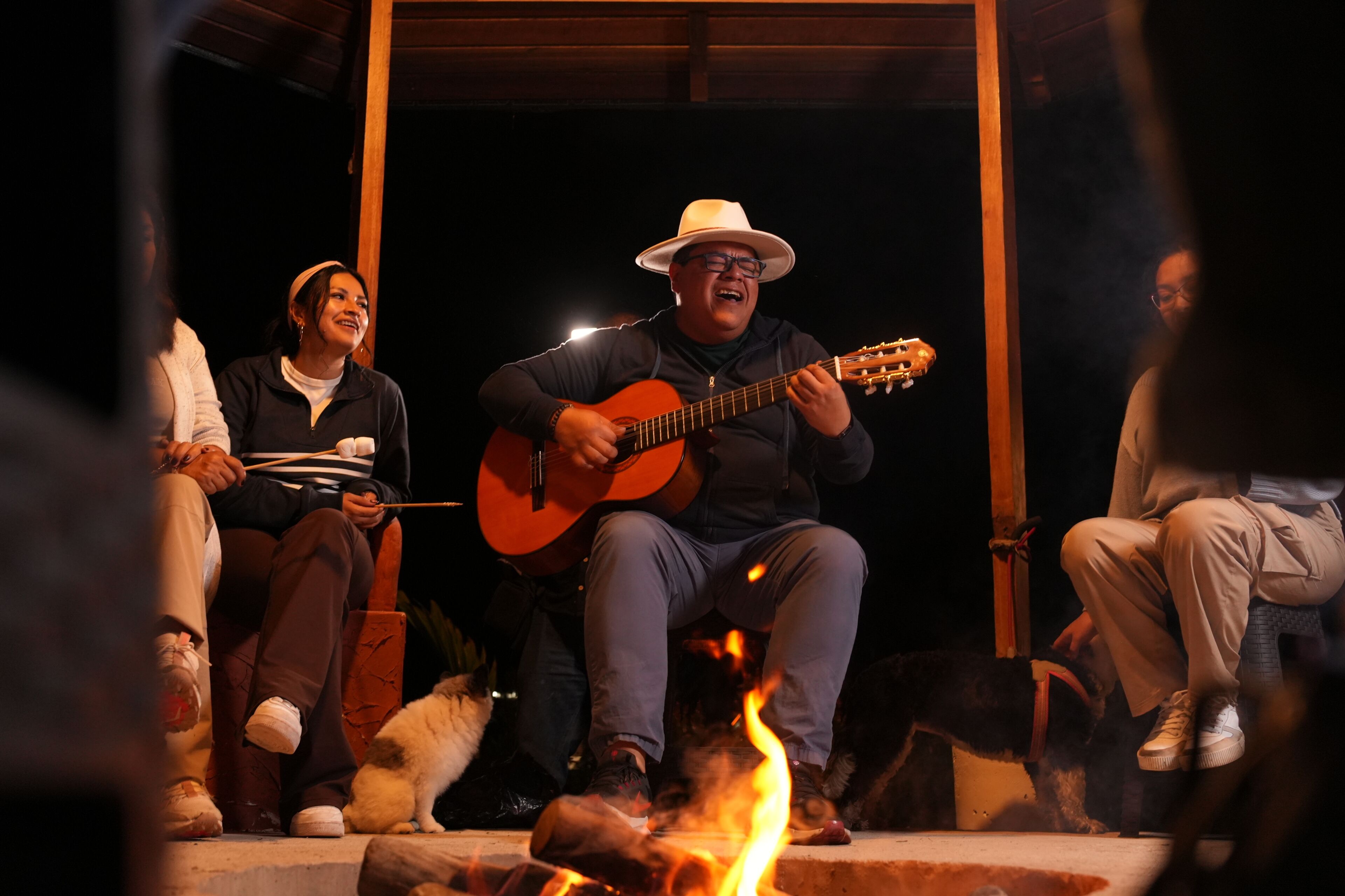 A person playing a guitar on a stage with a fire in the foreground.