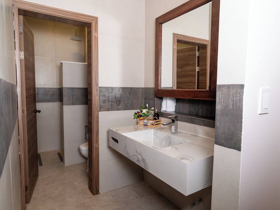 A bathroom with a wooden door, a white sink, a mirror, and a shower area.