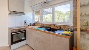 A modern kitchen with a built-in oven, a sink, and a window with a view of greenery.