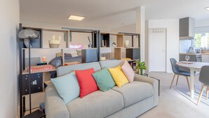 A modern living space with a sofa, dining table, and kitchen area.