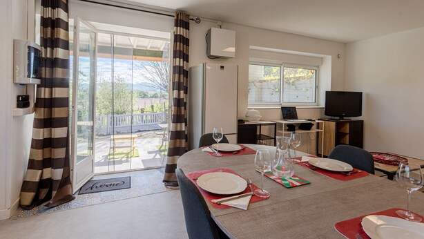 A dining area with a table set for four, a television, and a sliding glass door leading to an outdoor patio.
